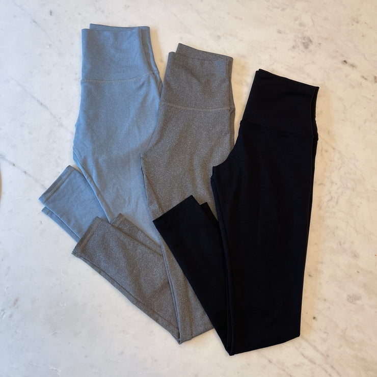 Three pairs of leggings with built-in underwear displayed on marble background: black legging, heather grey legging, heather sky blue legging