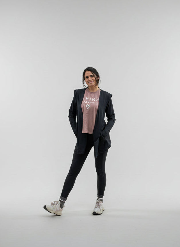 Woman wearing a black open activewear cardigan and activewear leggings on a white background