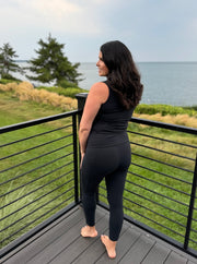 woman facing away looking wearing black leggings with pocket and a black workout top